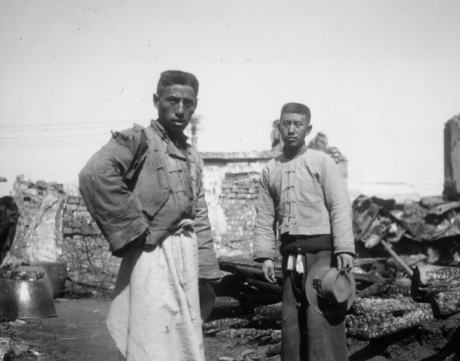 Two brothers stand outside of the remains of their house and shop in the southern section of Nanjing, which was badly damaged during the fighting.