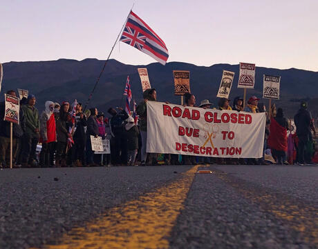 Demonstrators gather to block a road at the base of Mauna Kea