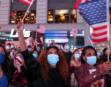 Masked crowd holding American flags. 