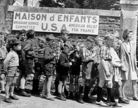 Children stand in front of a sign reading Maison d' Enfants USA