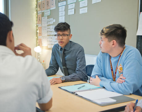 Male students discuss in a classroom.