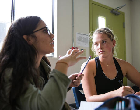 Two female students engage in classroom discussion.