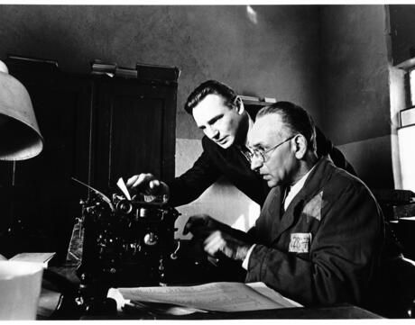 Picture of two men look at a typewriter.