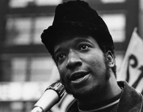 Black and white photo of Black Panther Party leader Fred Hampton speaking at a microphone 